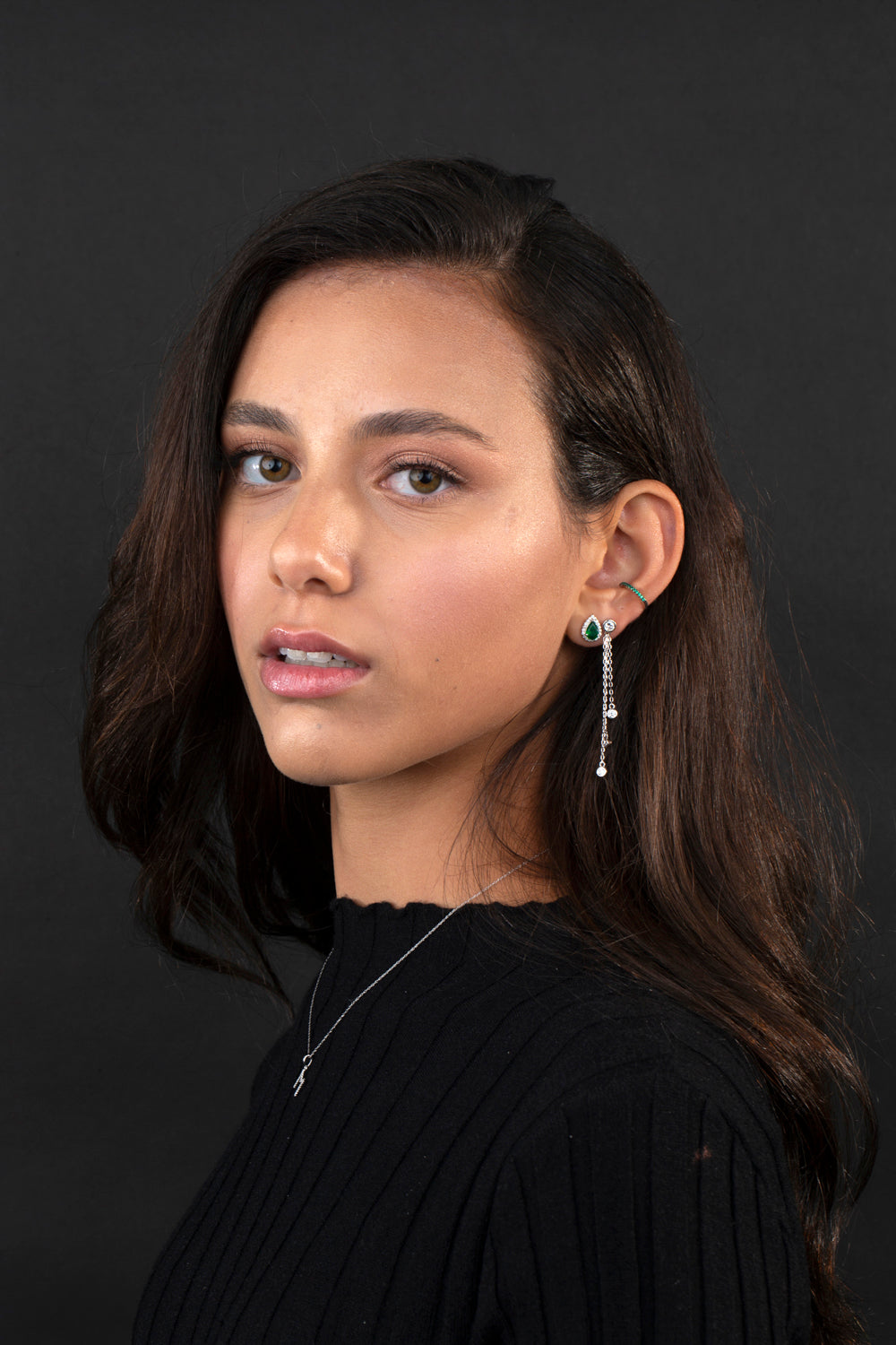 Girl with dark hair wearing multiple earrings 