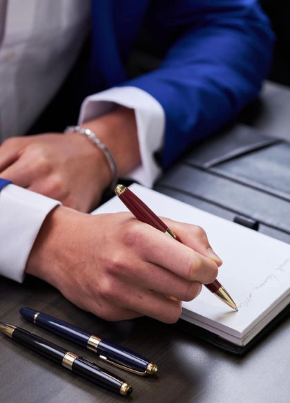 Luxury executive fountain pen collection – male professional writing in notebook at desk.